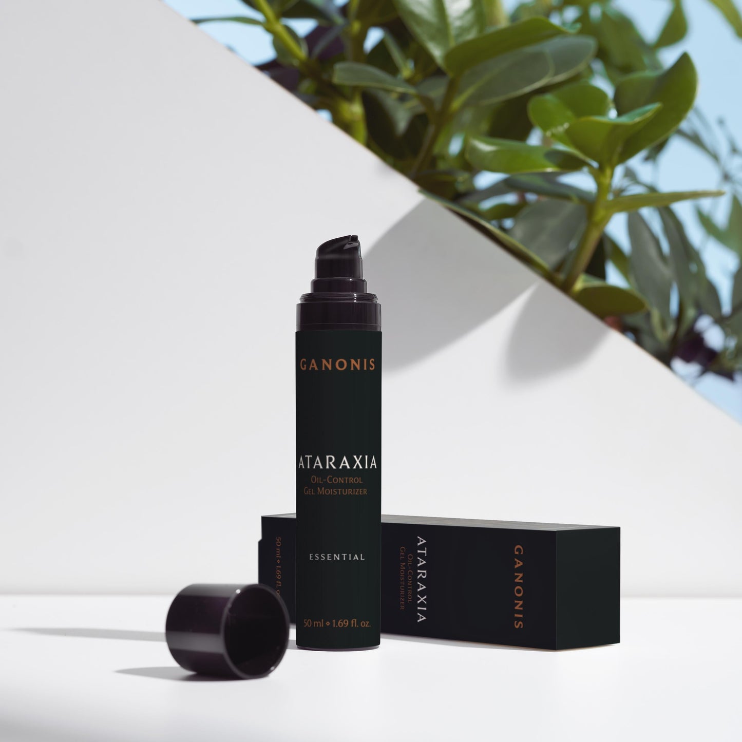 Cosmetic bottle and packaging with Ataraxia by GANONIS branding on a white surface with greenery in the background.