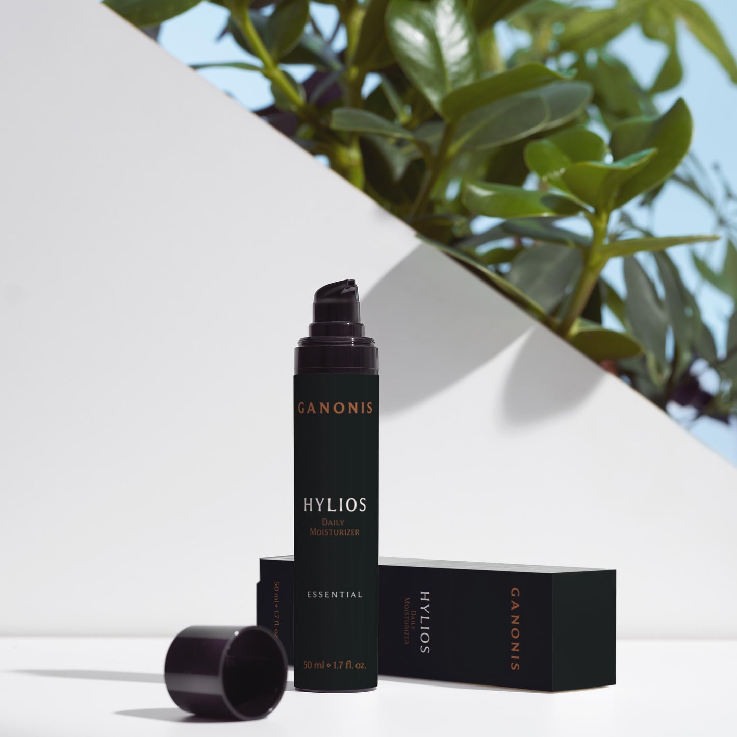 Ganonis Hylios skincare product with packaging on a white surface with green leaves in the background