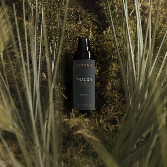 Dark bottle labeled THALON by GANONIS on a grassy background