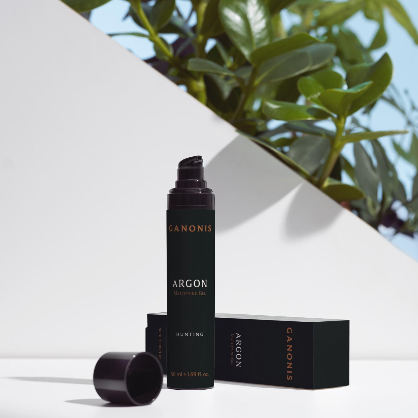 Cosmetic bottle and packaging of ARGON by GANONIS on a white surface with green leaves in the background